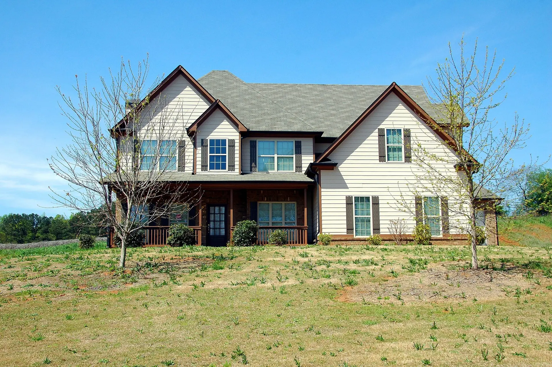 Two-story house with gabled roofs and a wide front lawn