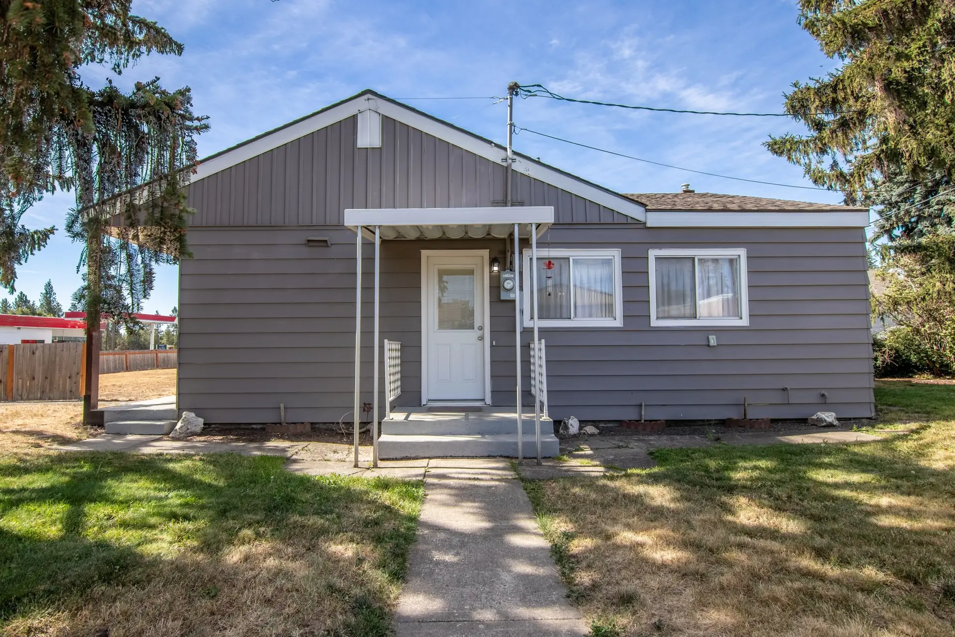 Small gray single-story house with a front stoop and a lawn