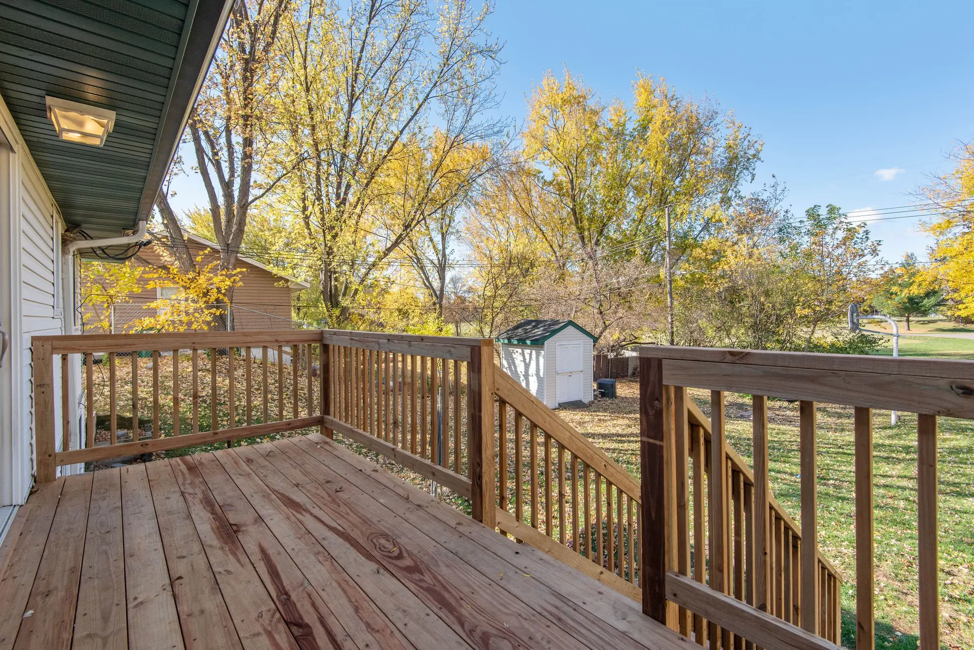 Wood deck with railings looking over an autumn backyard