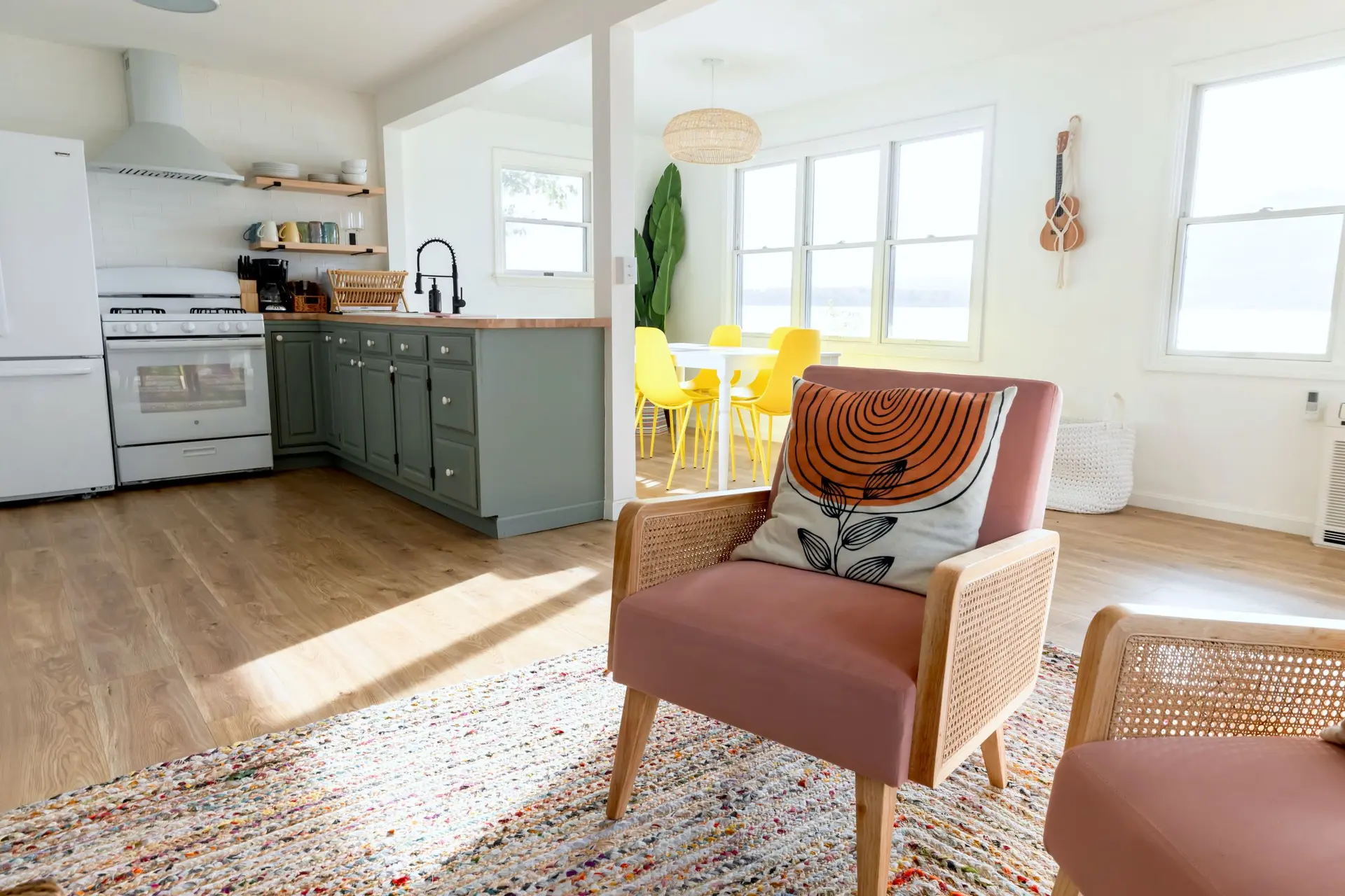 Kitchen with sage green cabinets opening to a sunny sitting area