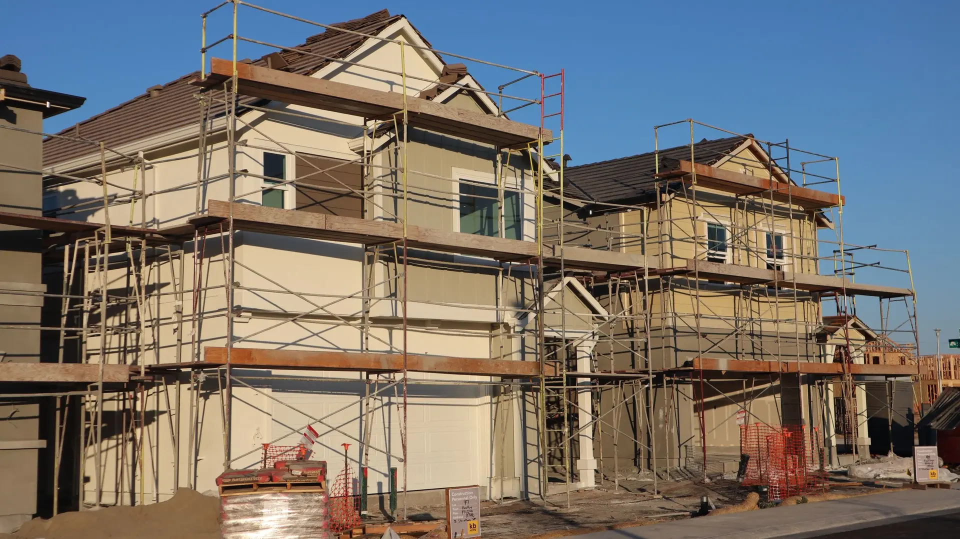 Two-story houses wrapped in scaffolding with stucco going on
