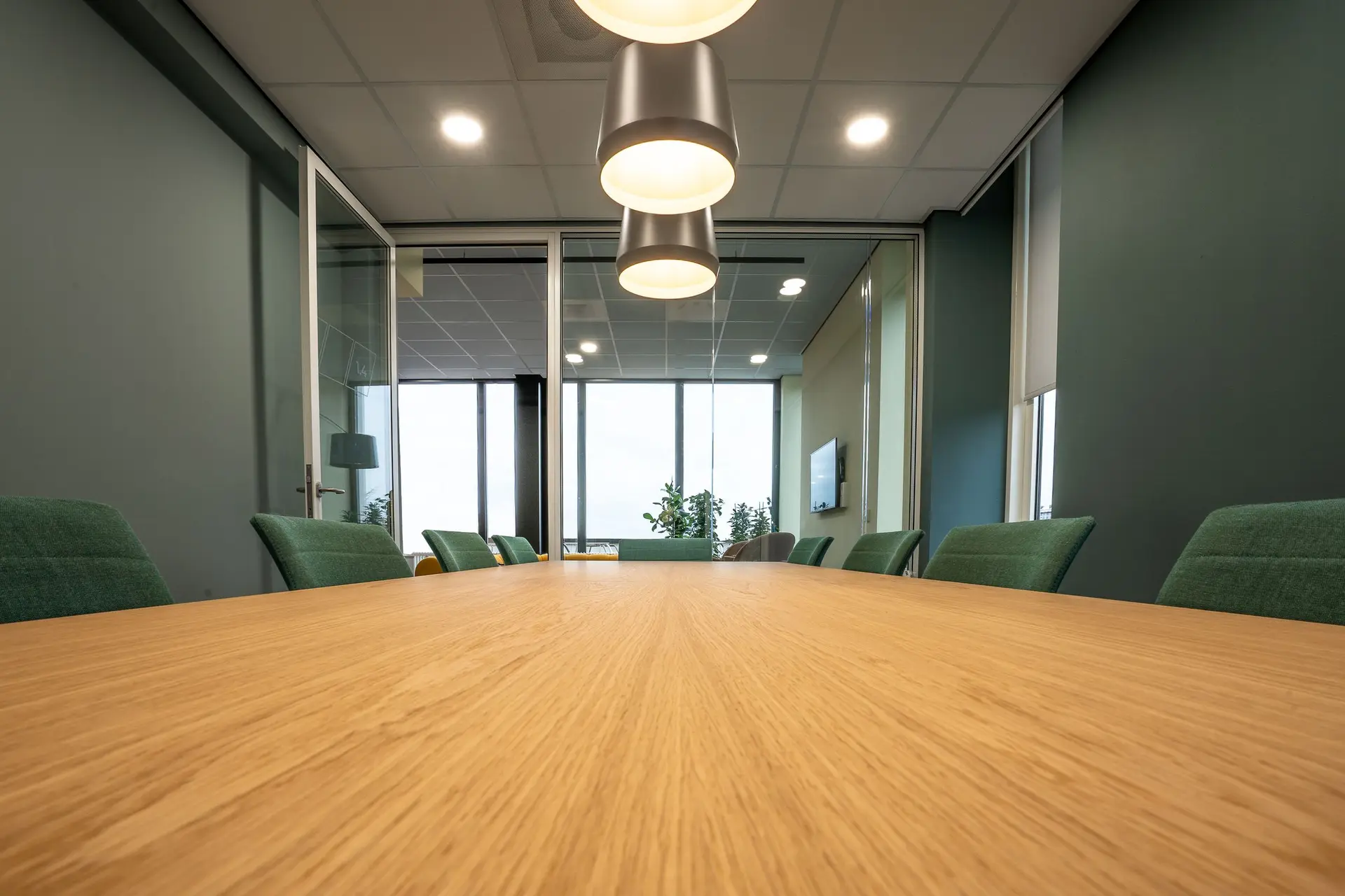 Conference room with a long wood table and green chairs