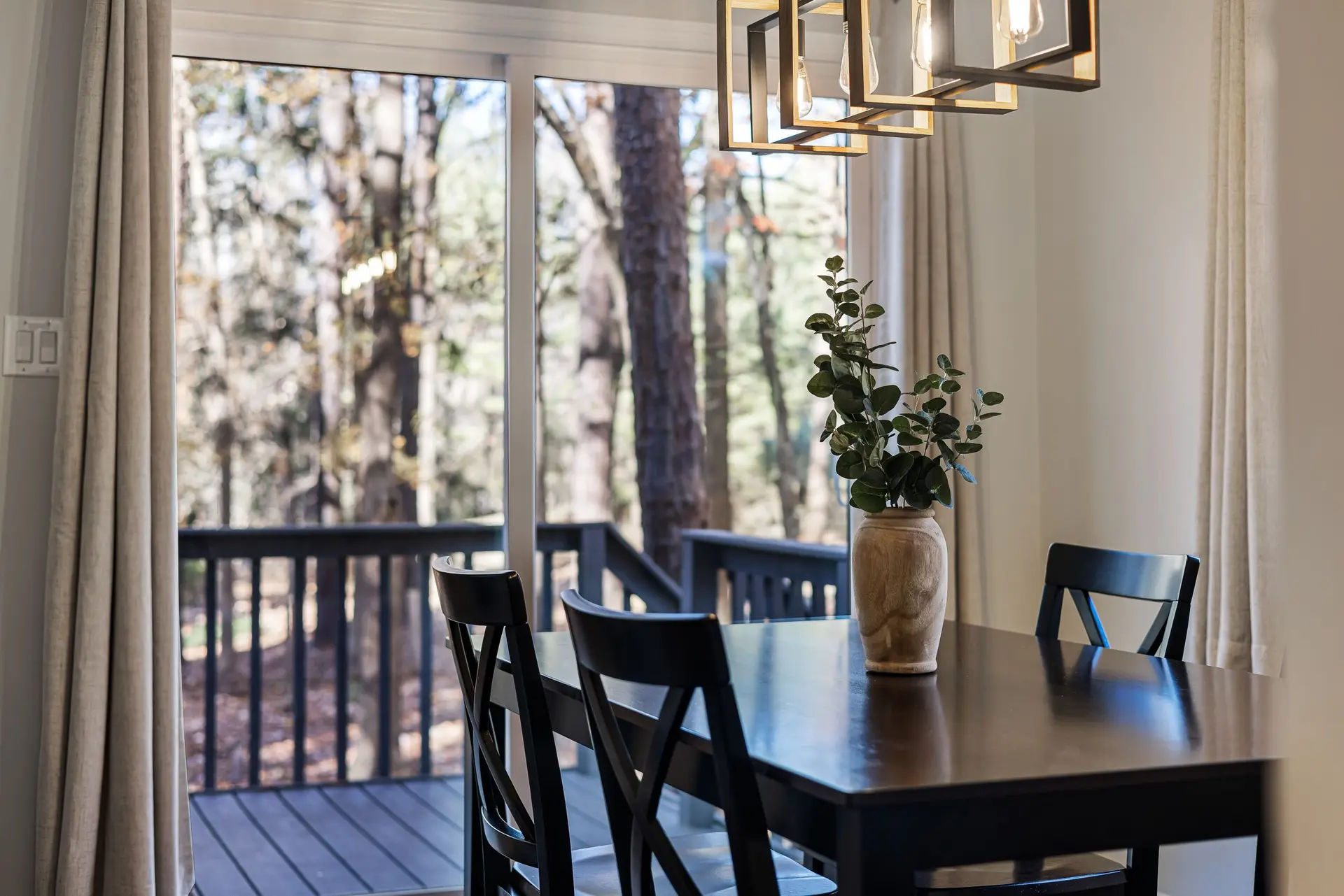 Dining room with a glass door onto a deck among pines